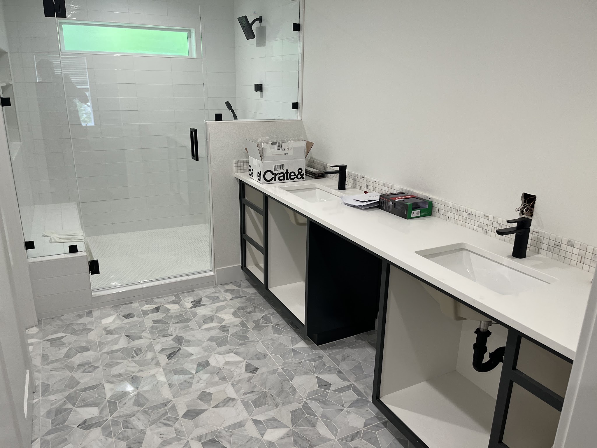 Finished bathroom with a tiled shower, double vanity and patterned marble floor