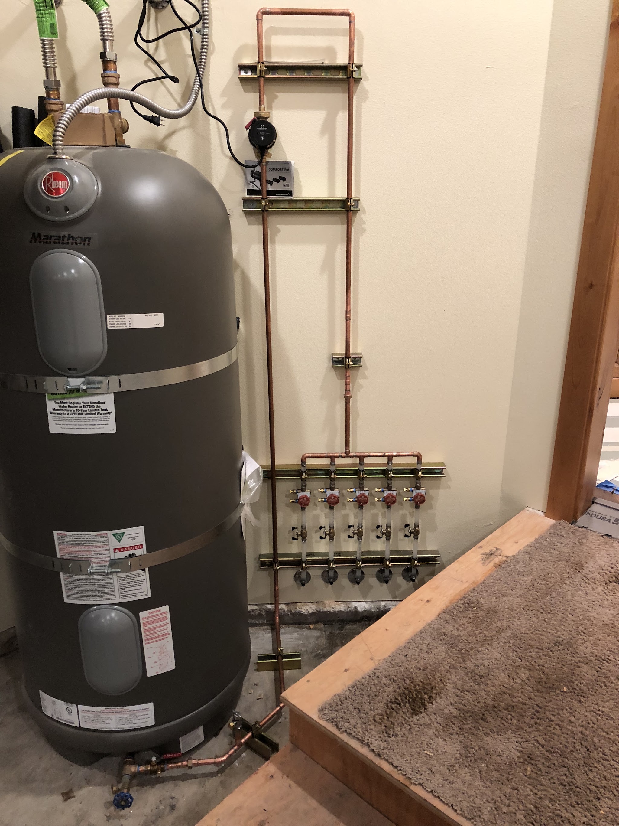 New water heater beside a hand built copper manifold with labelled shutoff valves