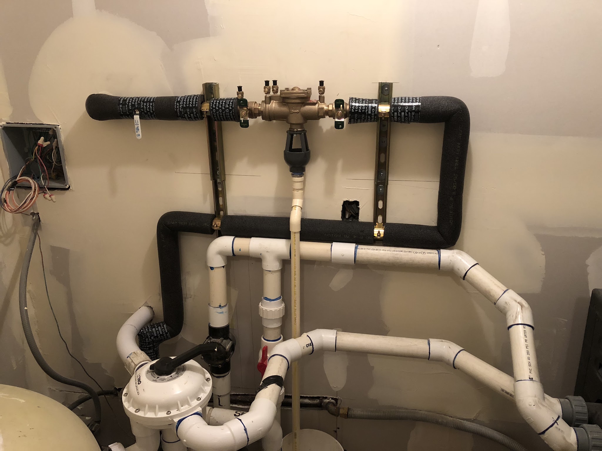 Backflow assembly and insulated supply lines mounted on a utility room wall
